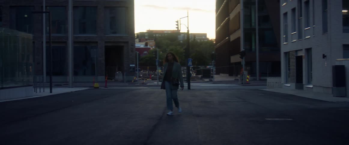 A woman walks across a quiet city street