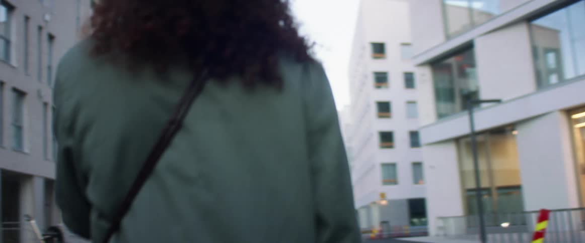 Black woman with curly hair makes a video call on the smartphone while walking down the street