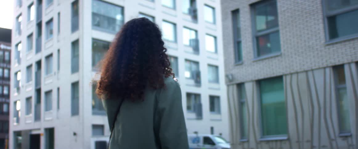 A woman walks in circles outside while having a video call on her cell phone