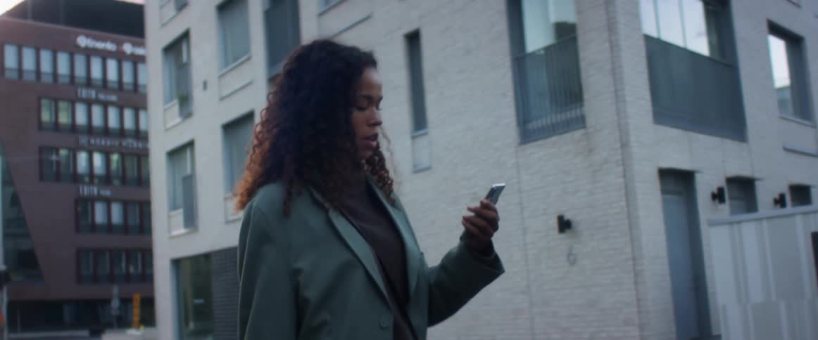A young woman walks in a downtown area and talks to her phone