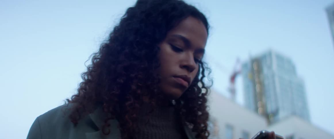 A young woman in a downtown area looks at her cell phone