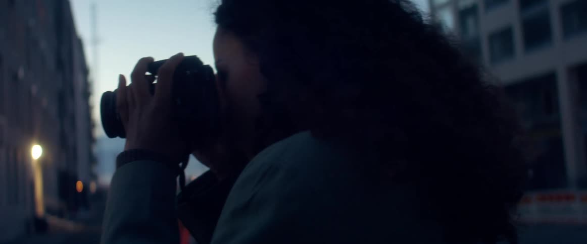 Woman takes pictures in the streets of a city in late evening