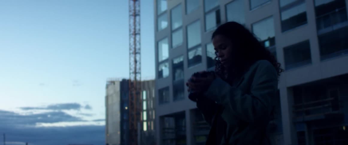 A young female photographer gazes at the tall buildings around her before raising her camera to take a photograph