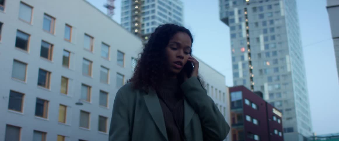 A woman is in a downtown city and talking on a cellphone