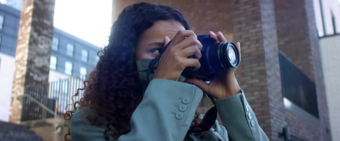 Young woman takes pictures with a camera next to a building in the city