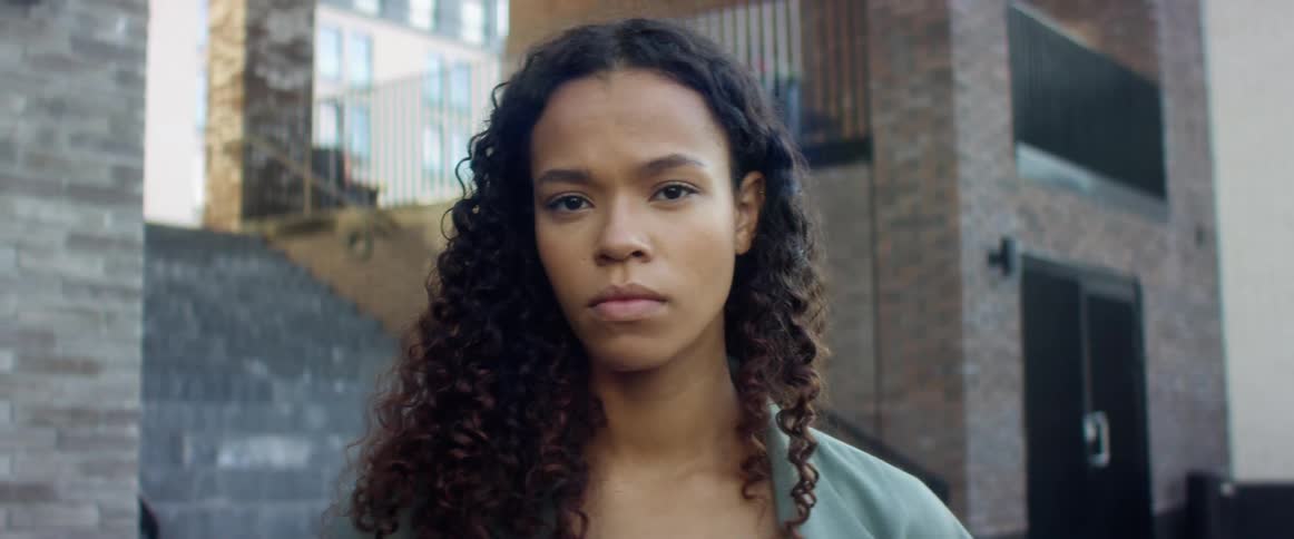 A young black woman blinks as she stares into the camera