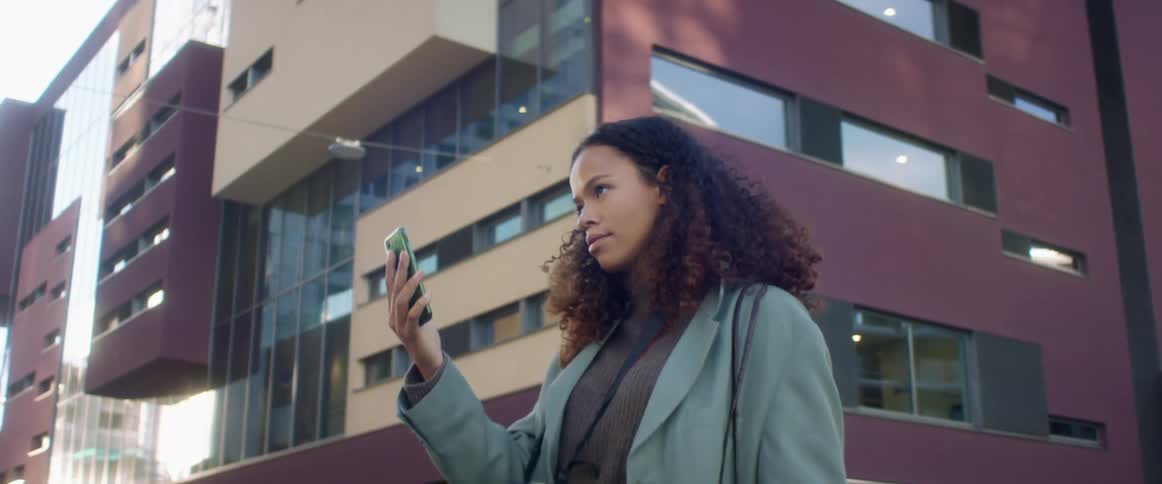 Woman answers a video call on her smartphone outside a building in the city