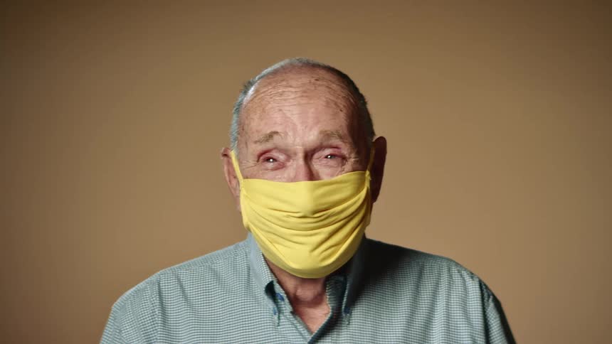An elderly man is wearing a face mask indoors