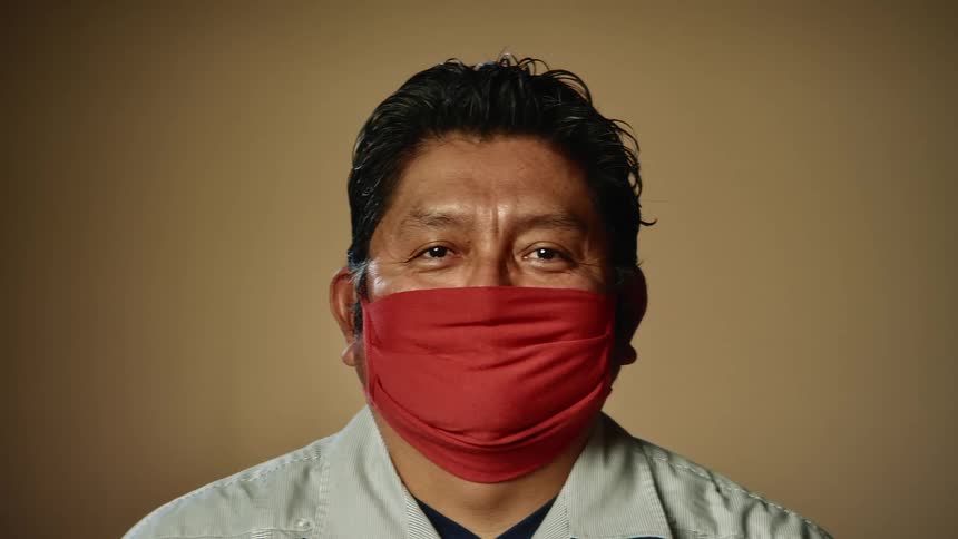 A man wears a mask over his mouth while standing in a studio
