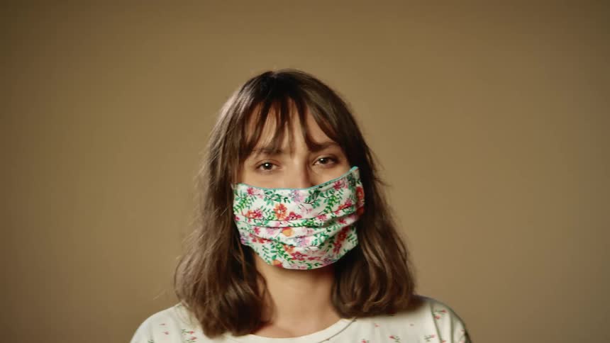 A woman is standing in a room and wearing a face mask
