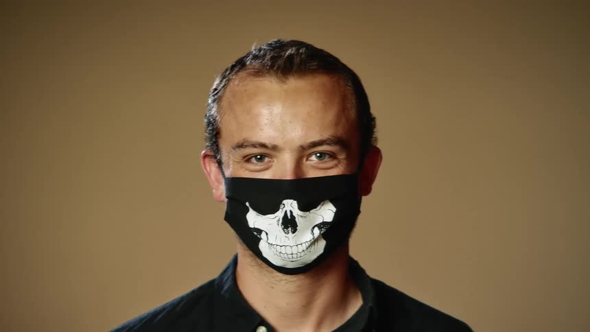 A man is standing in a room while wearing a face mask
