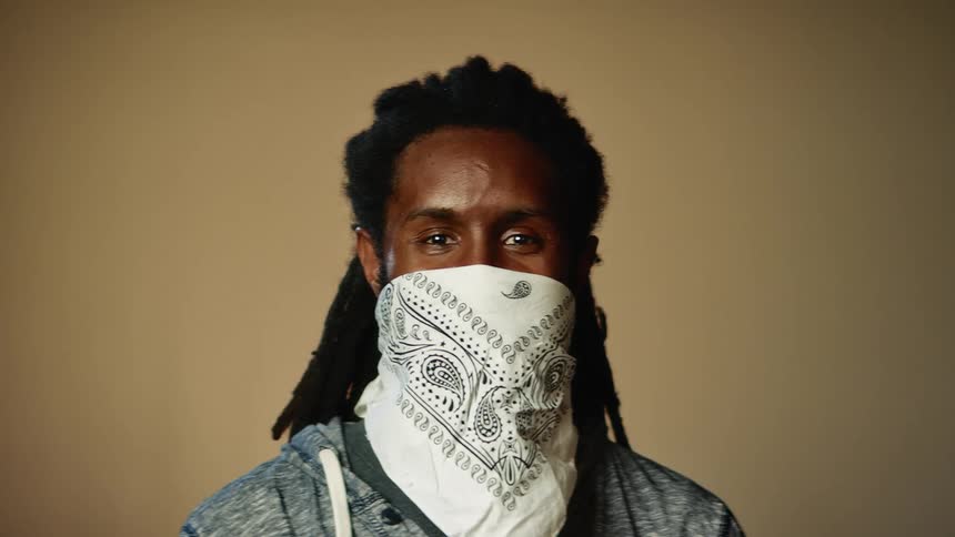 A man is wearing a bandana over his face