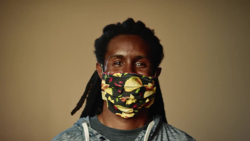A young black man with a mask on poses for a portrait