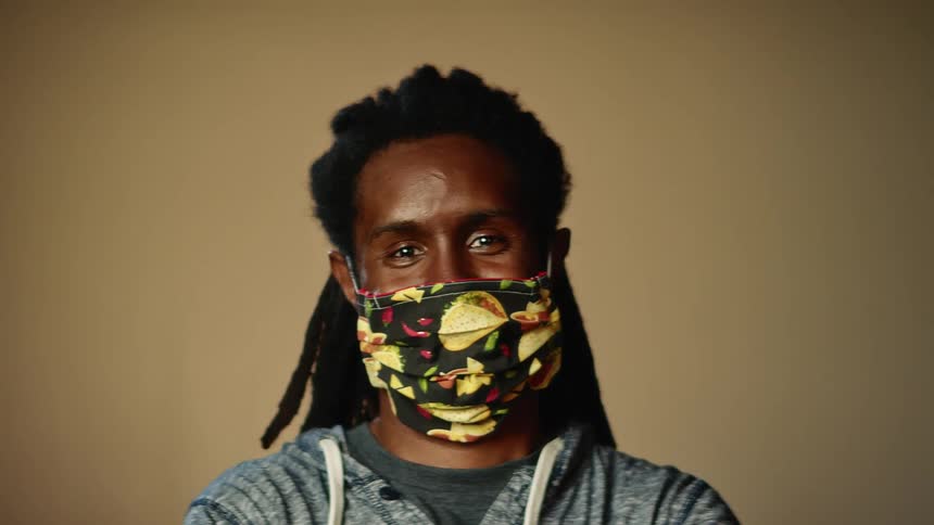 Man wearing face mask with taco print smiles and shrugs