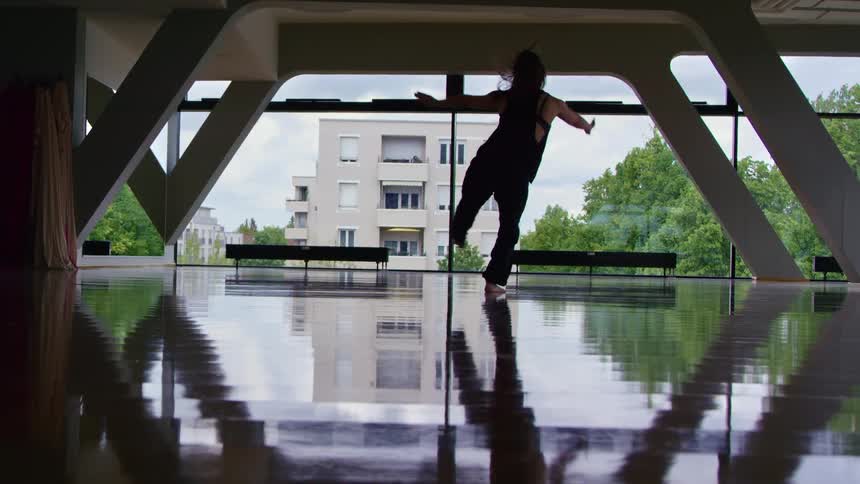 A woman jumps and spins as she dances indoors