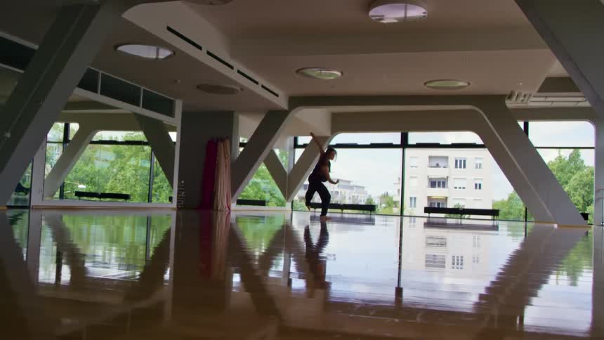 A woman dances alone in a spacious dance studio