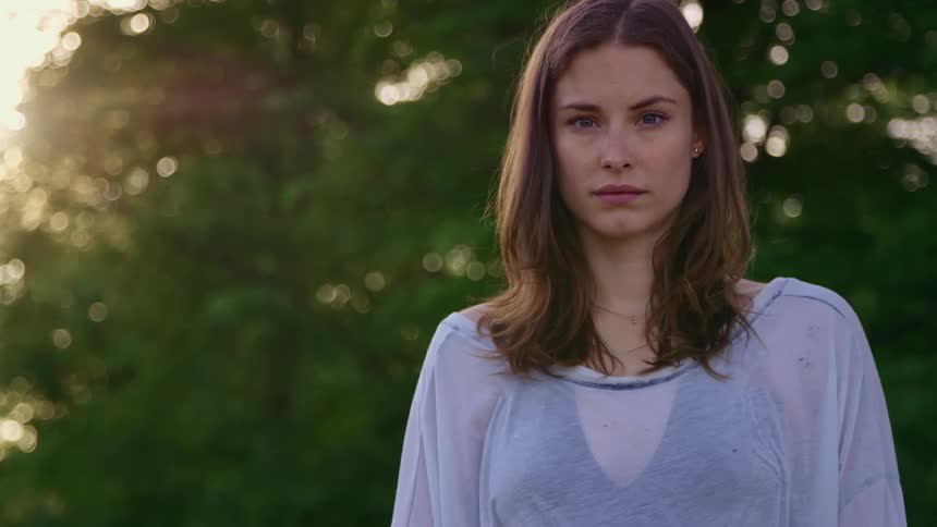 A woman is standing outdoors at dusk