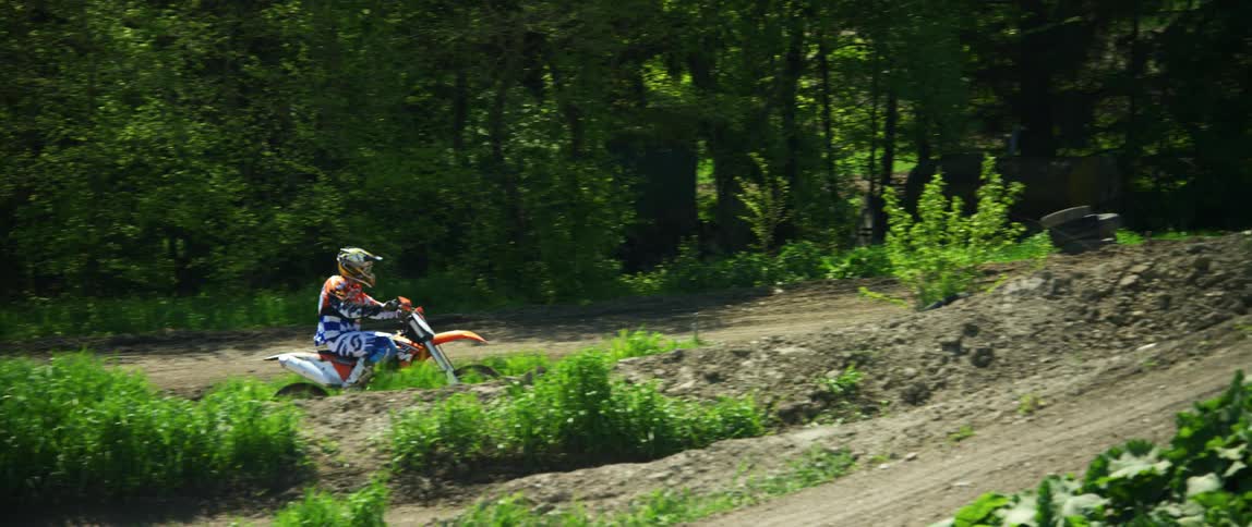 A motorcyclist rides a dirt bike along an offroad motorcycle course