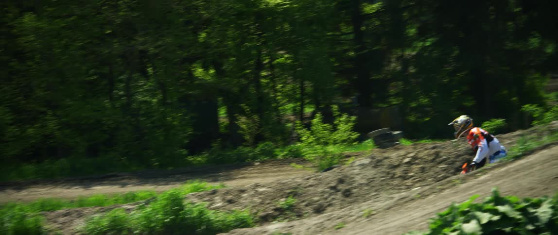 A motocross rider goes airborne after speeding up a hill on an offroad motorcycle track