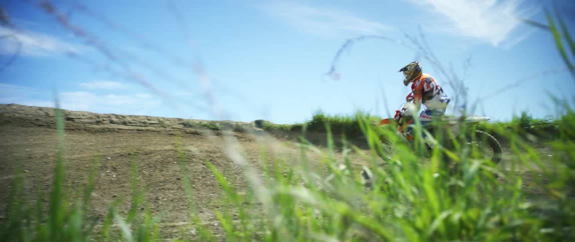 Man drives off road motocross motorcycle on a dirt track at day