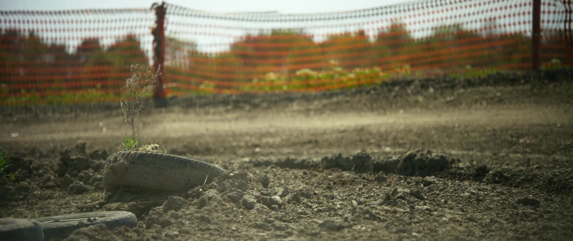 A person drives their dirt bike along a dusty and rocky outdoor motocross course