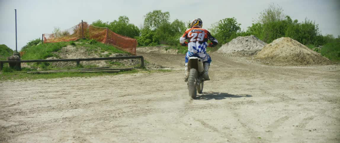 Man rides an off road dirt bike on an outdoors motocross track