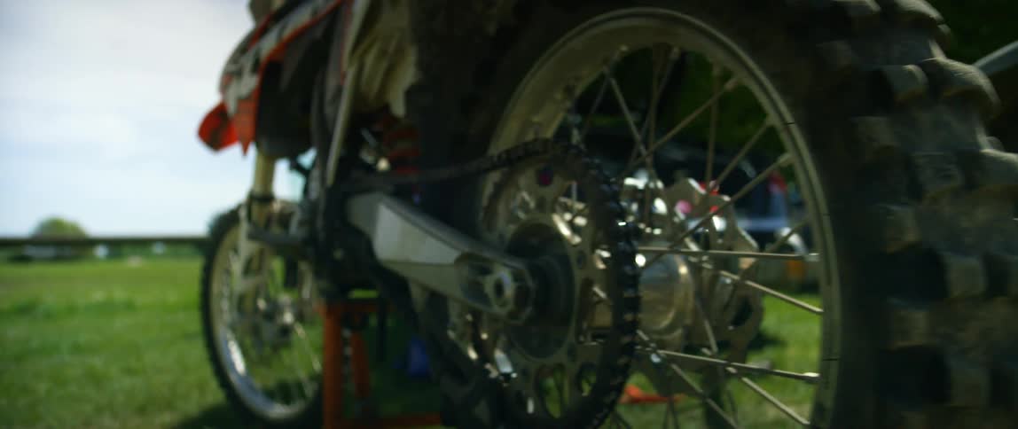 A dirt bike sits on a field next to other vehicles