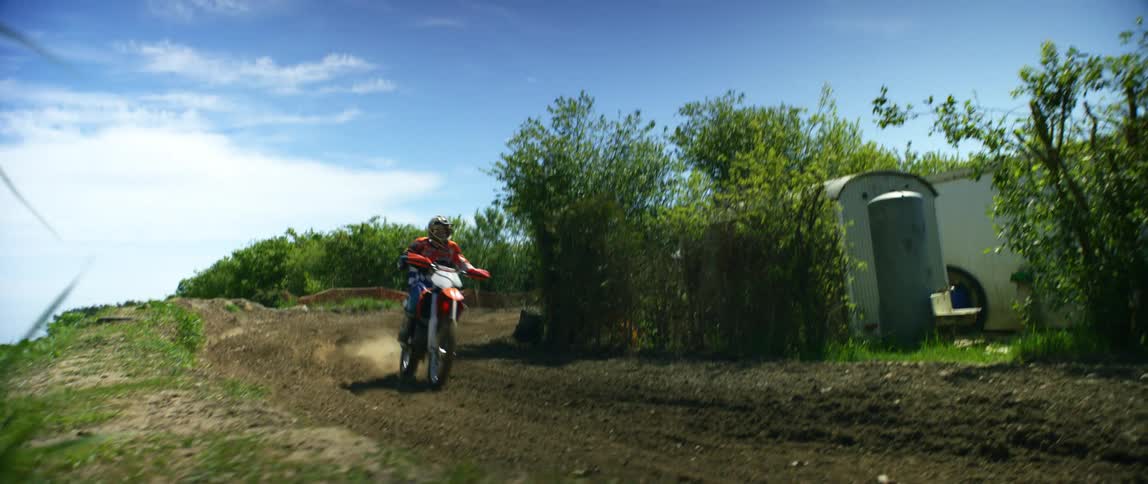 A motocross rider goes airborne after riding up a dirt ramp on an offroad motorcycle track