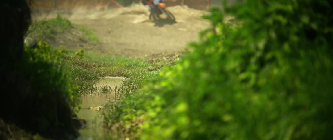 A person drives a motorcross motorcycle on a dirt road