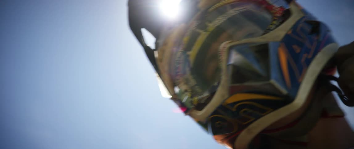 A man adjusts the chin strap on his crash helmet on a sunny day