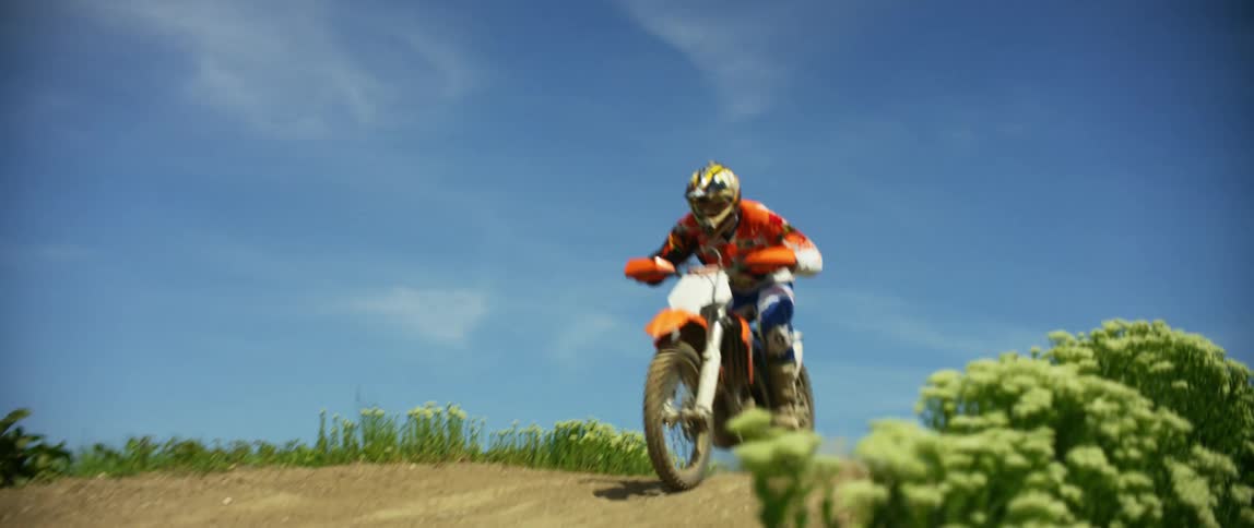 Man drives a dirt bike over a slope on a motocross track