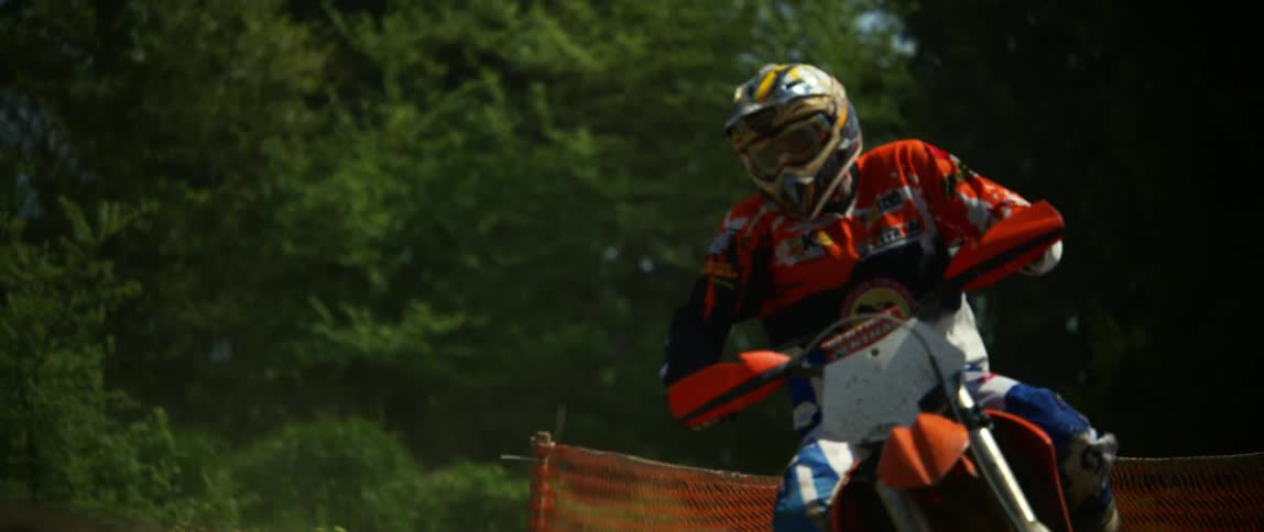 A motocross rider rides his motorcycle down a sloped trail