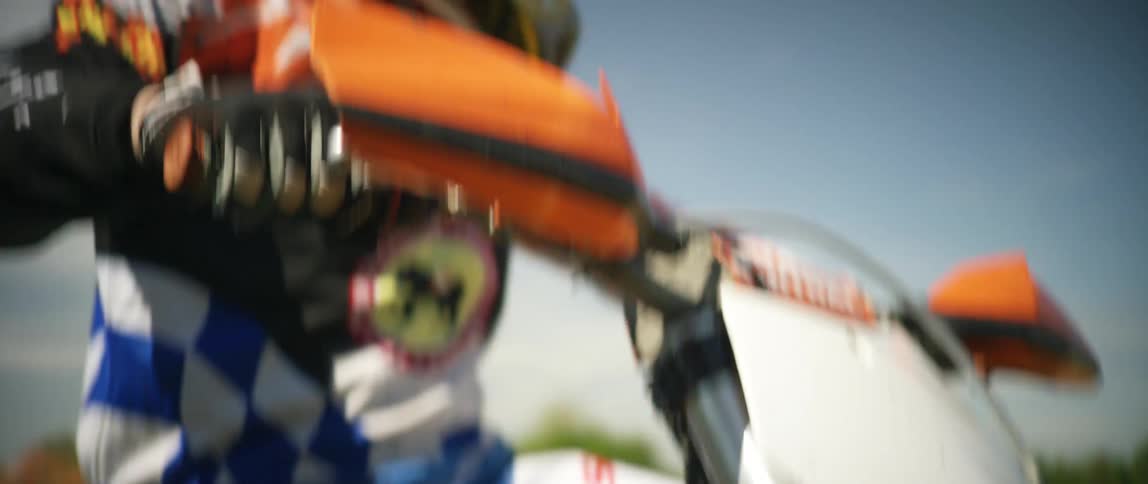 A person sitting upon a dirt bike starts its engine and drives off