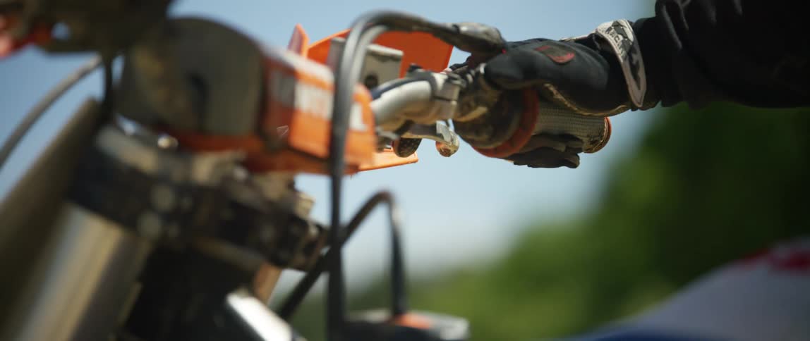 A motorcyclist sits on a rental dirt bike outdoors on a sunny day
