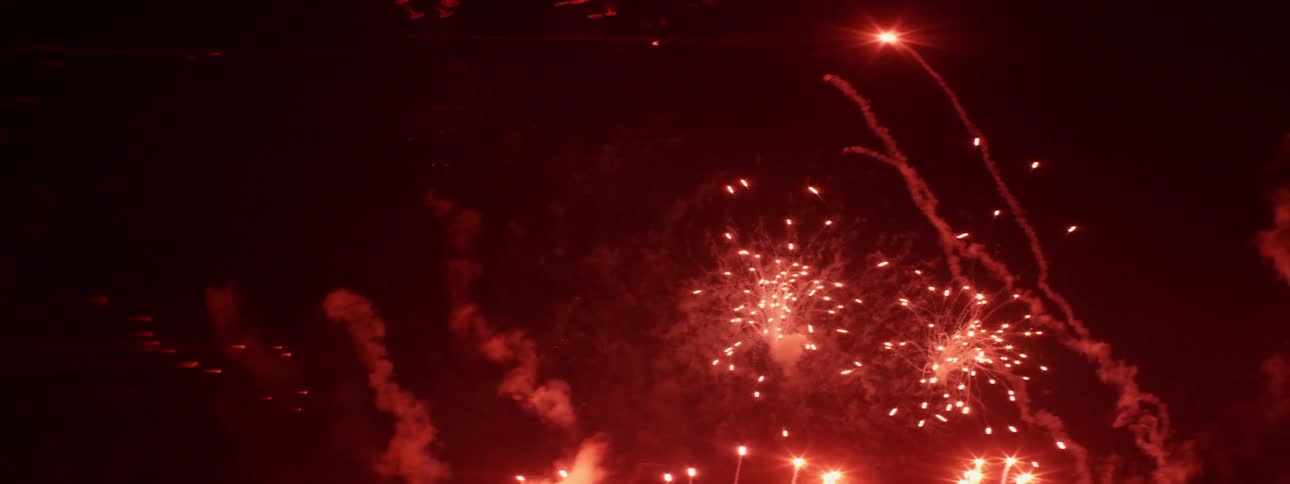 Red and yellow fireworks explode and spread in the night sky