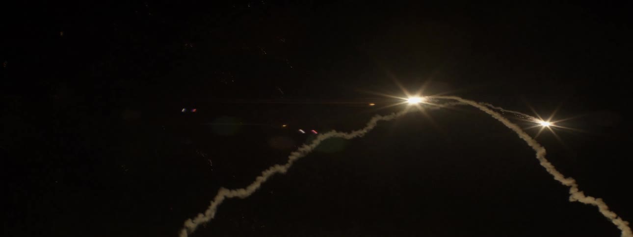 A ground level view of fireworks flying skyward at night