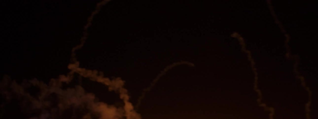 Fireworks fly into the night sky leaving a trail of smoke and sparks behind them