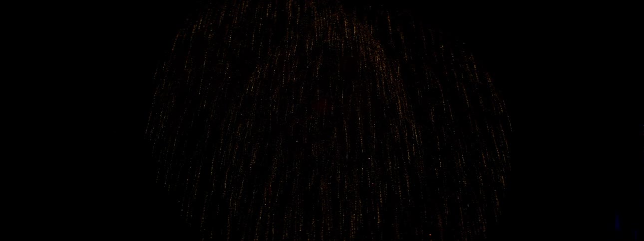 Red and yellow fireworks explode in the night sky