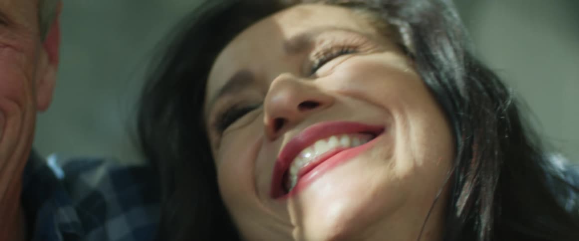 Woman smiles as she talks to husband who is drinking a beer