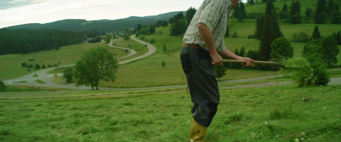 A man works in a field as two people bike past