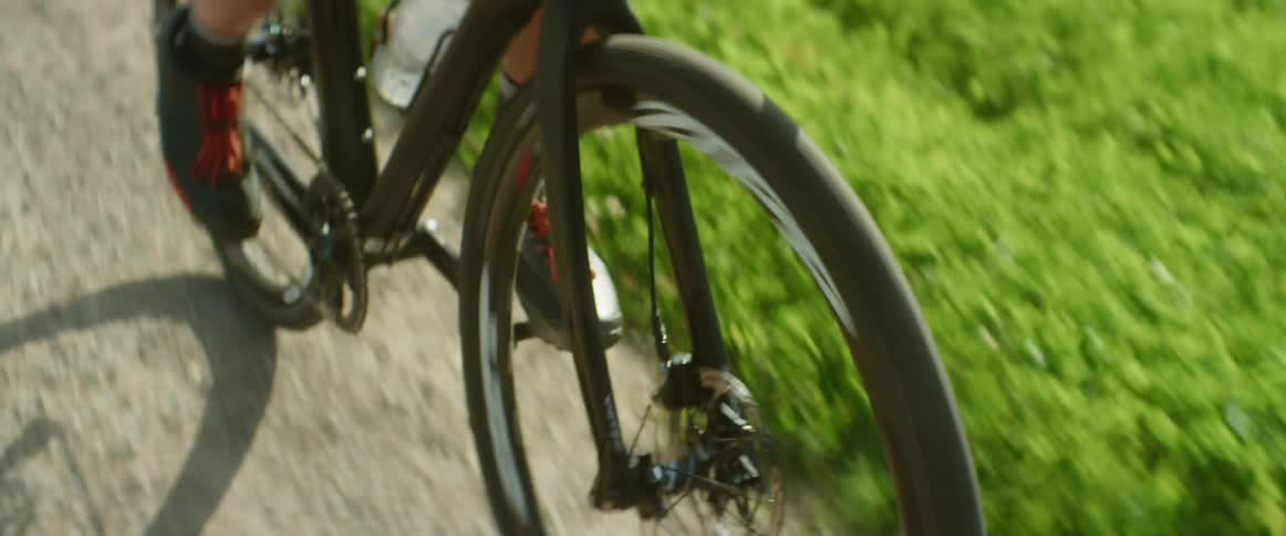 A man is bicycling along a dirt path surrounded by grass in the daytime