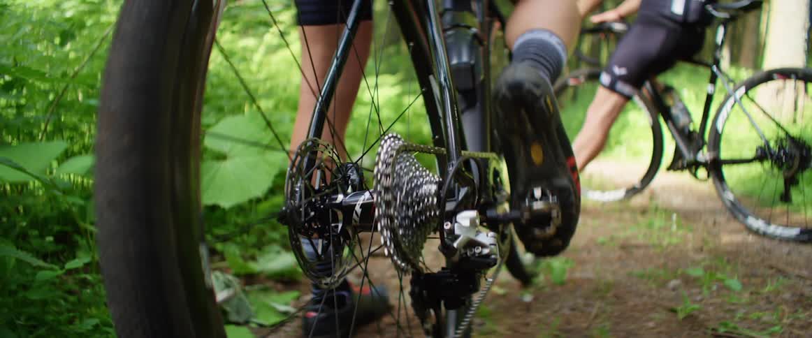 Bicyclist moves bike pedal while standing near another waiting bicyclist
