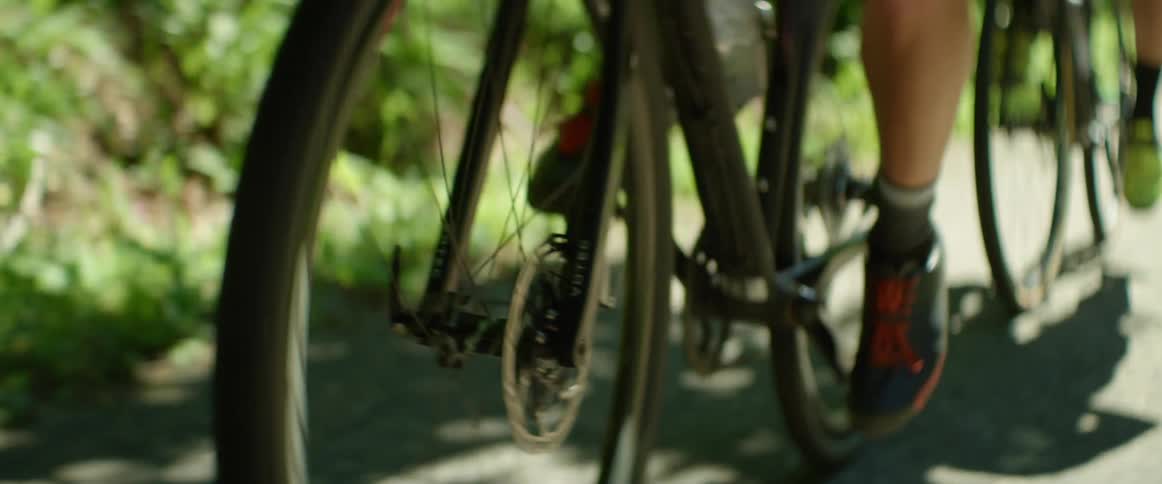 Young fit man wearing sports clothing rides a bicycle up a dirt road
