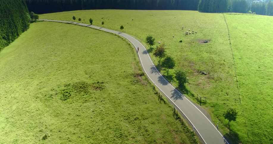 An aerial view of two bicyclists riding on a rural road on a summer day