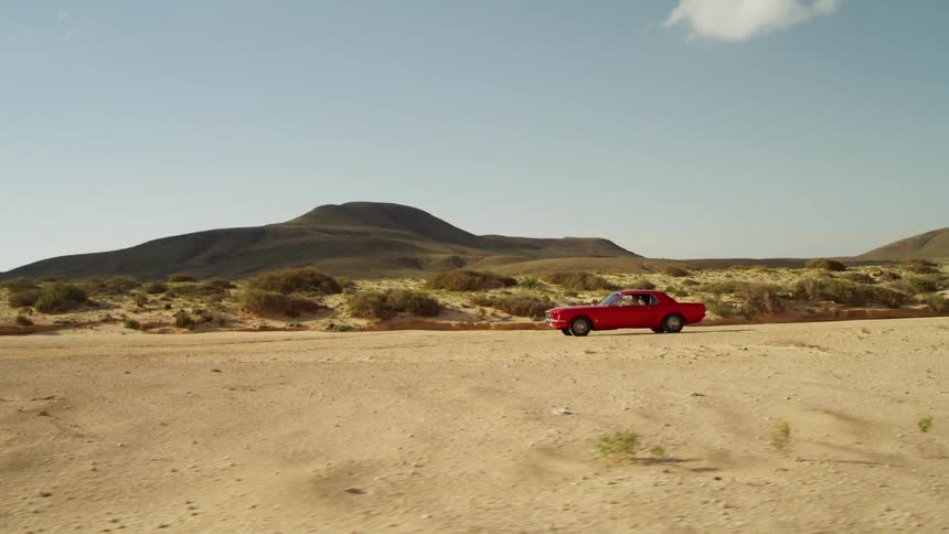 A car is driving in a desert area