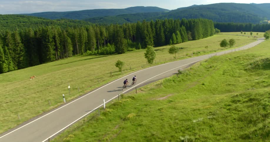 Two men are riding bikes in a rural area