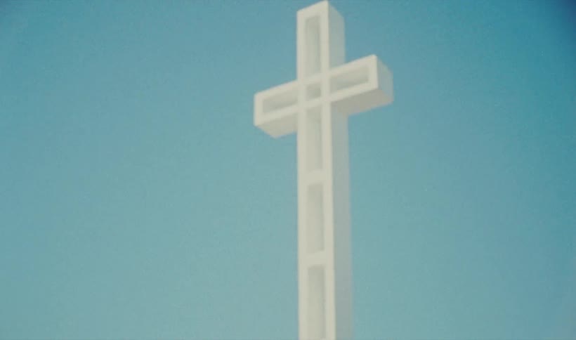A white cross with the sky and clouds in the background