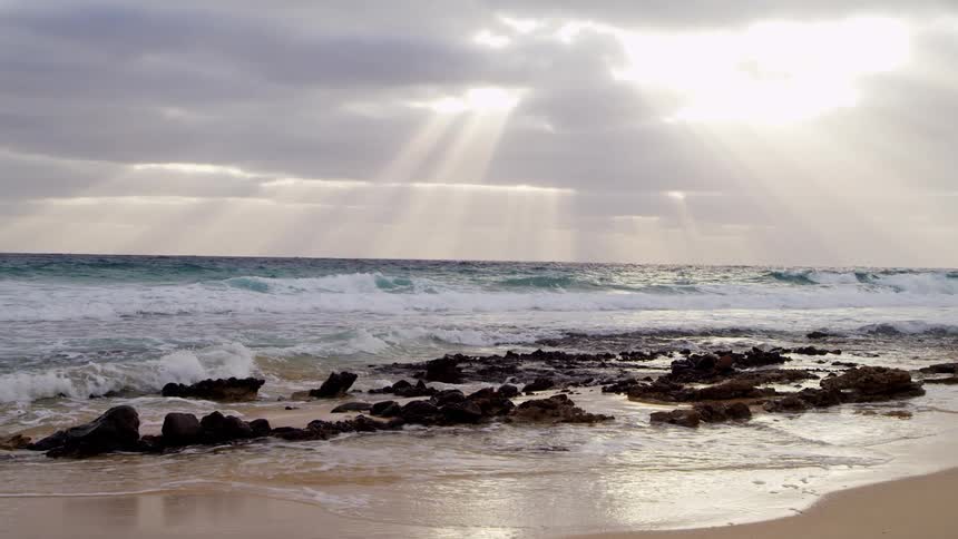 Sun beams shine from the sky over the rough sea