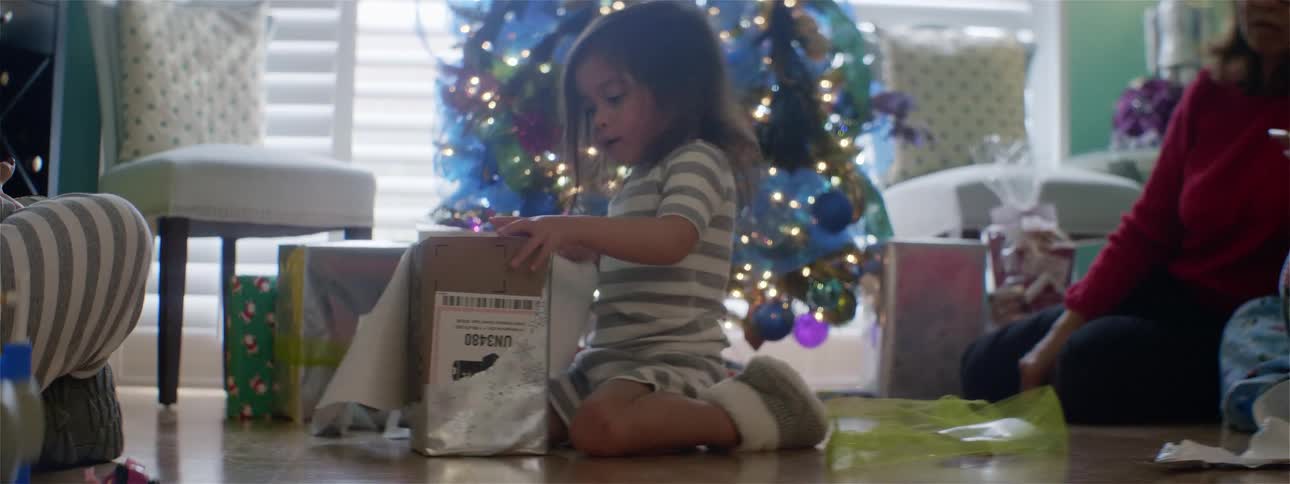 Girl opens gifts under a christmas tree at home