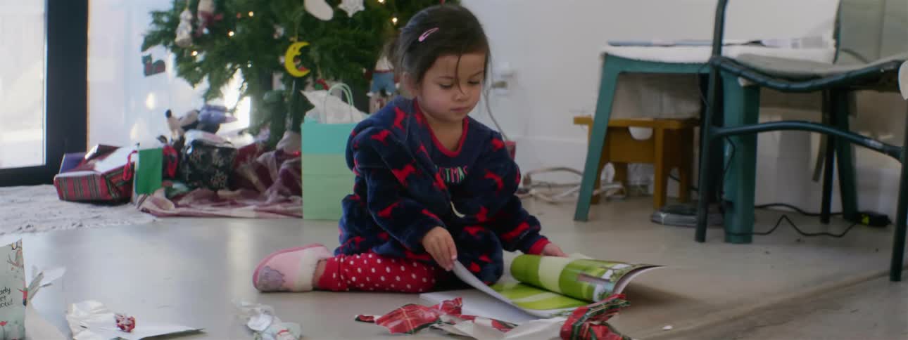 Girl sits on the ground reading a book she got as a christmas present
